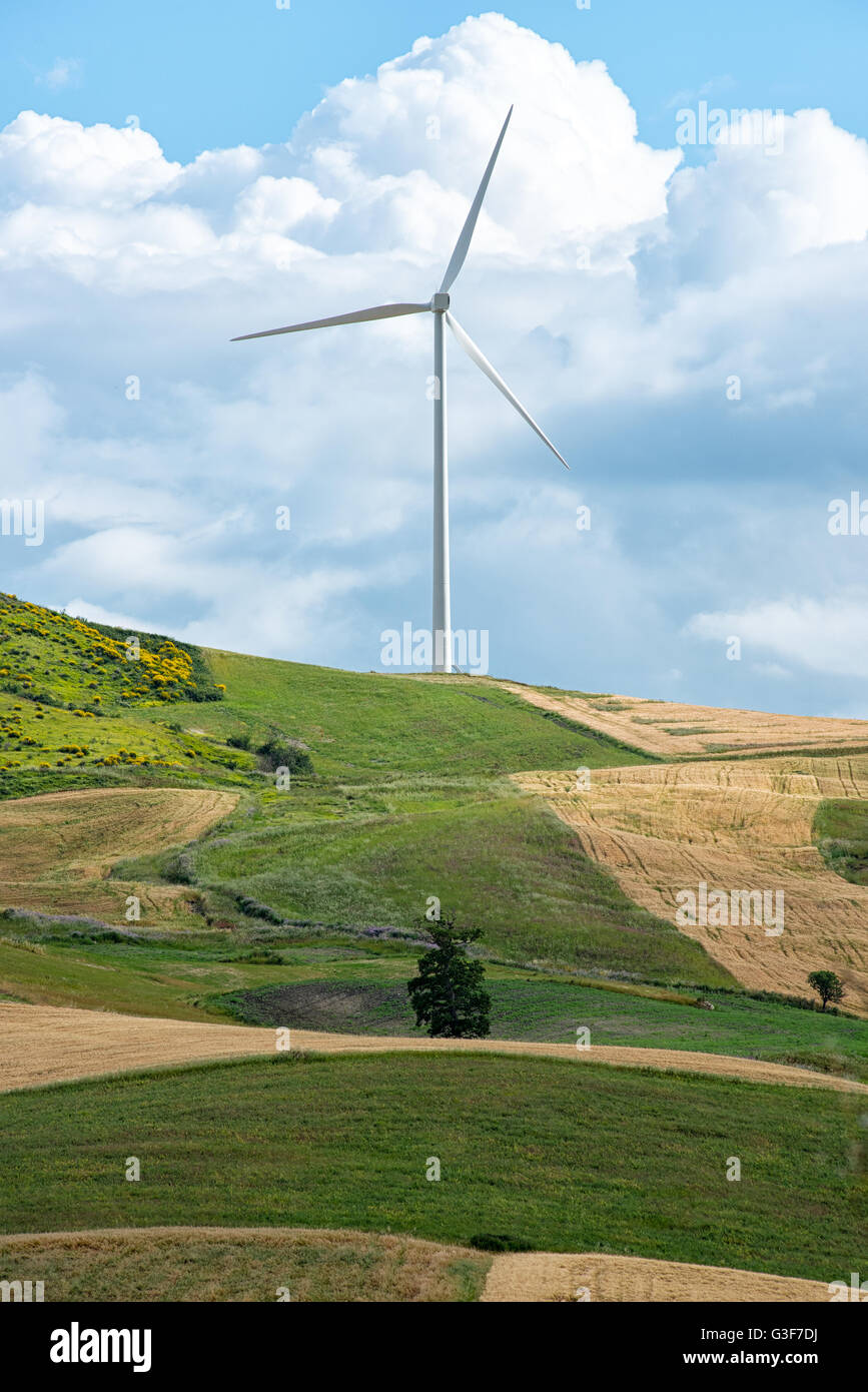 Seule éolienne fournissant de l'énergie renouvelable au sommet d'une colline rural agricole avec des champs et des prés en dessous contre un nuage Banque D'Images