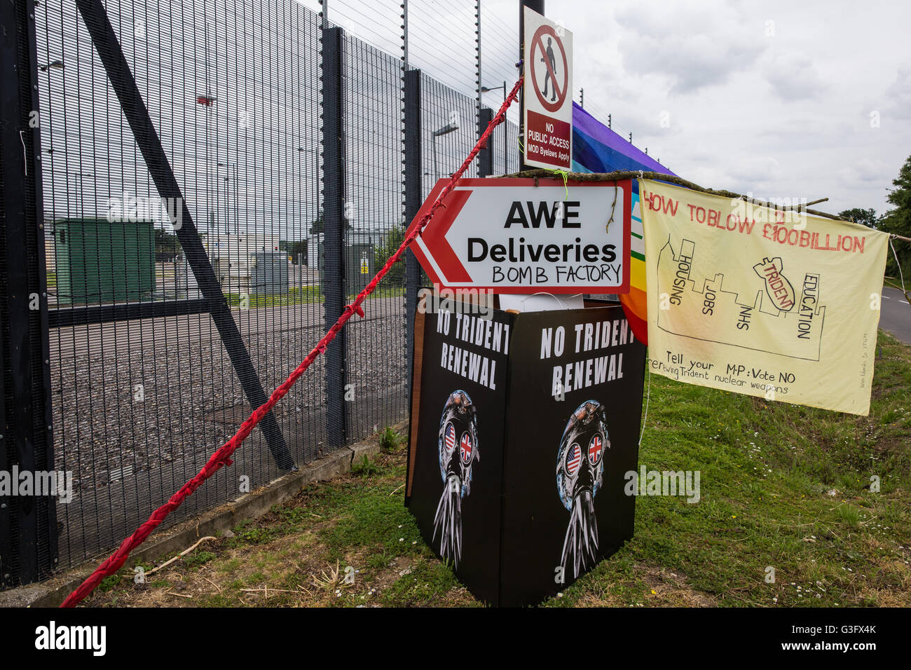 Burghfield, UK. 11 Juin, 2016. Une bannière, des pancartes et des graffitis à l'extérieur de l'AWE Burghfield le cinquième jour d'un blocus de l'entrée des livraisons dans le cadre d'un mois d'action contre le renouvellement du Trident destiné "aux blocus, à occuper et à perturber l'usine" responsable de l'assemblage final de Trident monté des têtes nucléaires. Credit : Mark Kerrison/Alamy Live News Banque D'Images
