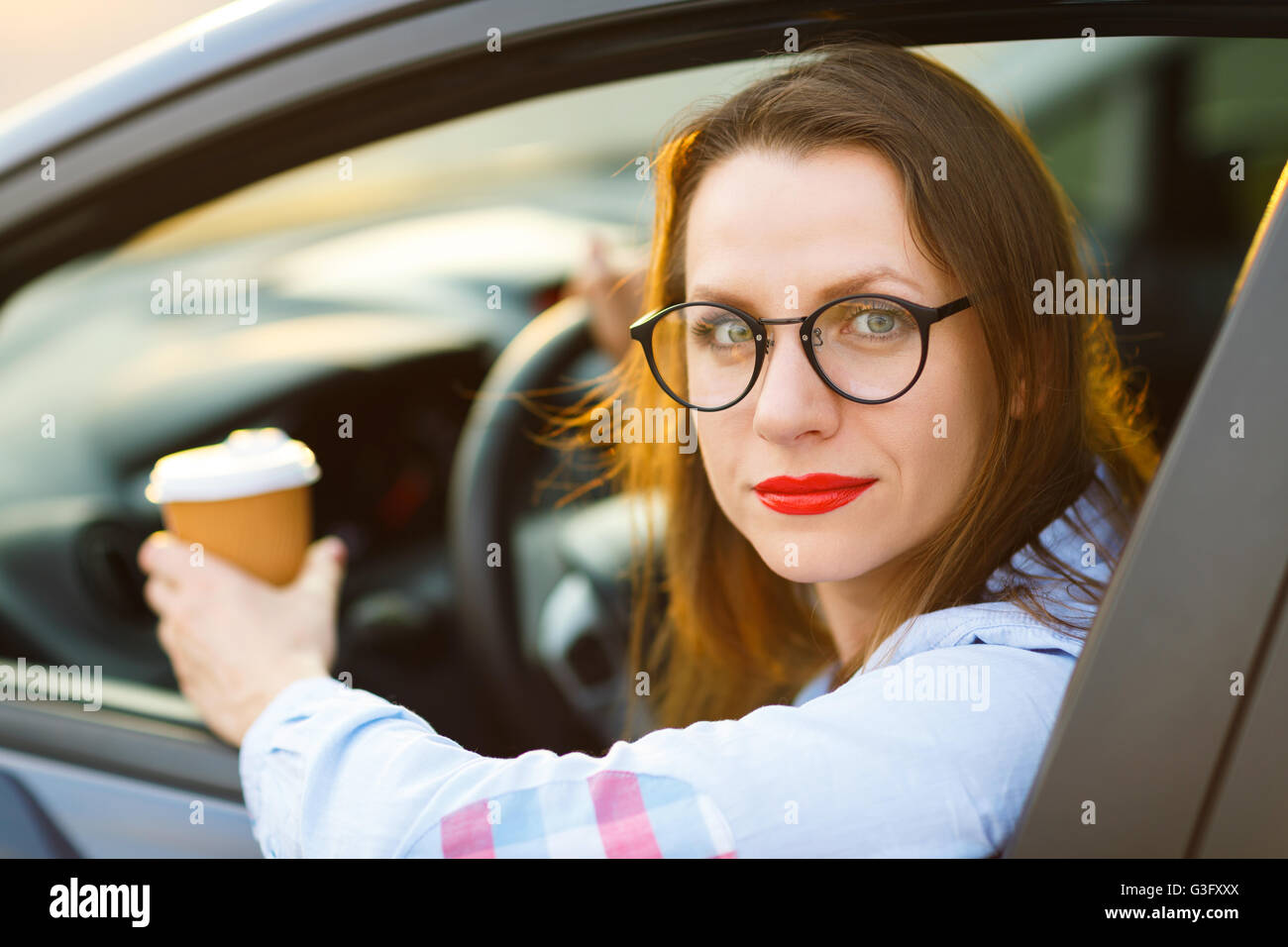 Happy young woman with coffee pour aller conduire sa voiture Banque D'Images