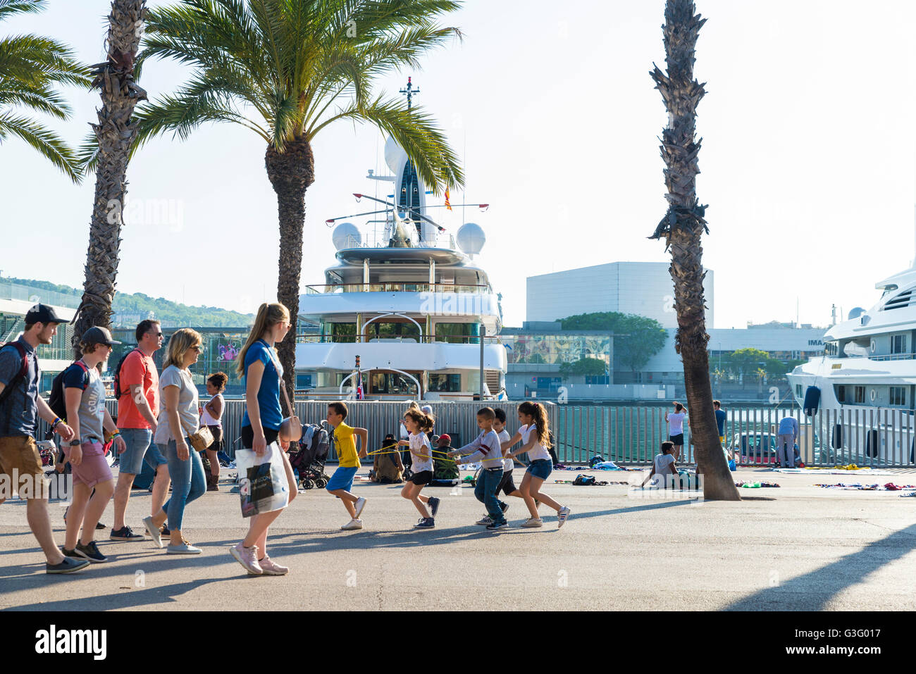 Enfant jouant dans le port Vell avec des yachts de luxe dans l'arrière-plan à Barcelone, Catalogne, Espagne Banque D'Images