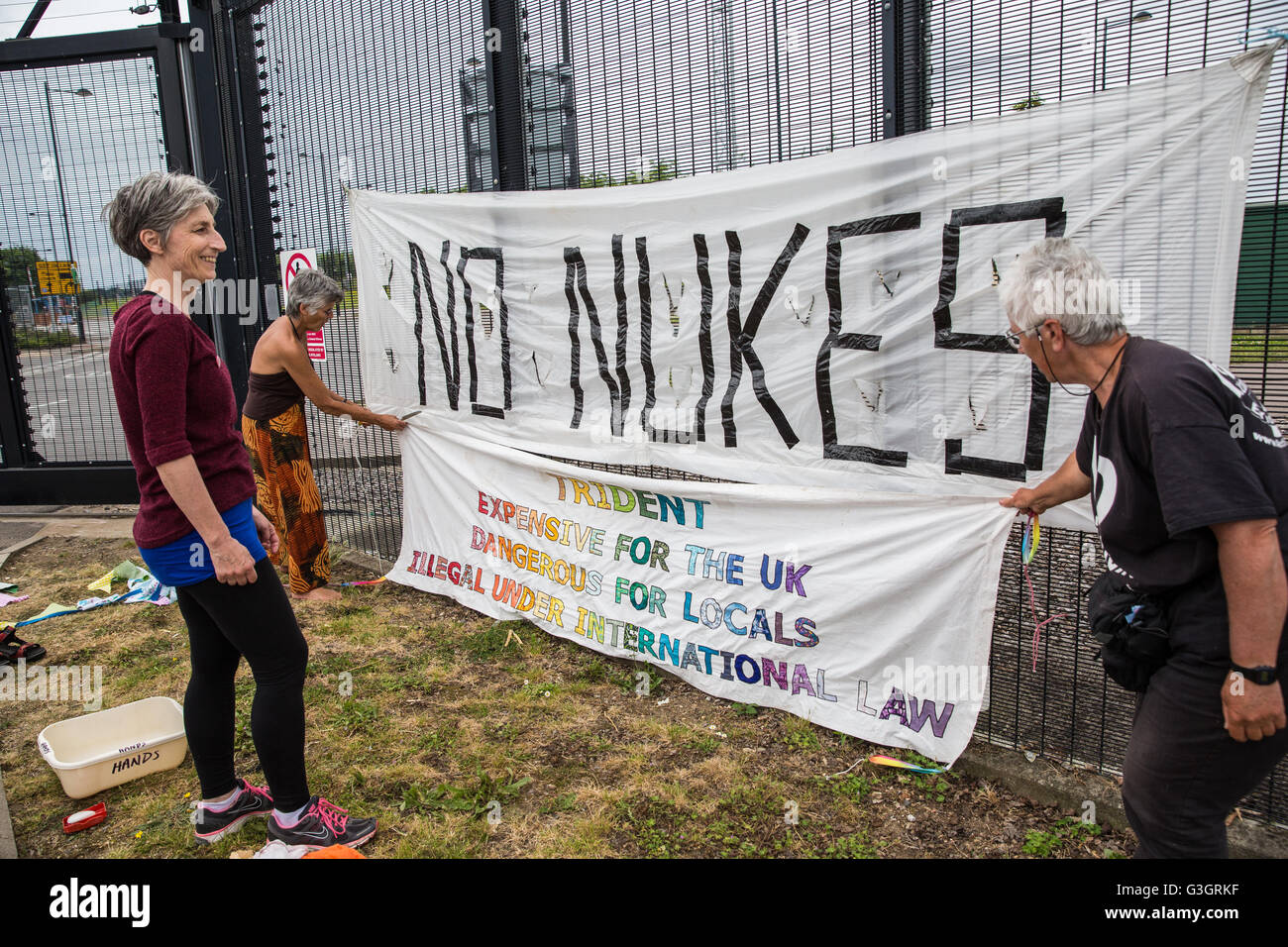 Burghfield, UK. 11 Juin, 2016. Ex-Greenham les militants de la paix commune accrocher des bannières sur la clôture périphérique de l'AWE Burghfield sur la cinquième journée consécutive d'un blocus de l'entrée des livraisons dans le cadre d'un mois d'action contre le renouvellement du Trident destiné "aux blocus, à occuper et à perturber l'usine" responsable de l'assemblage final de Trident monté des têtes nucléaires. Credit : Mark Kerrison/Alamy Live News Banque D'Images