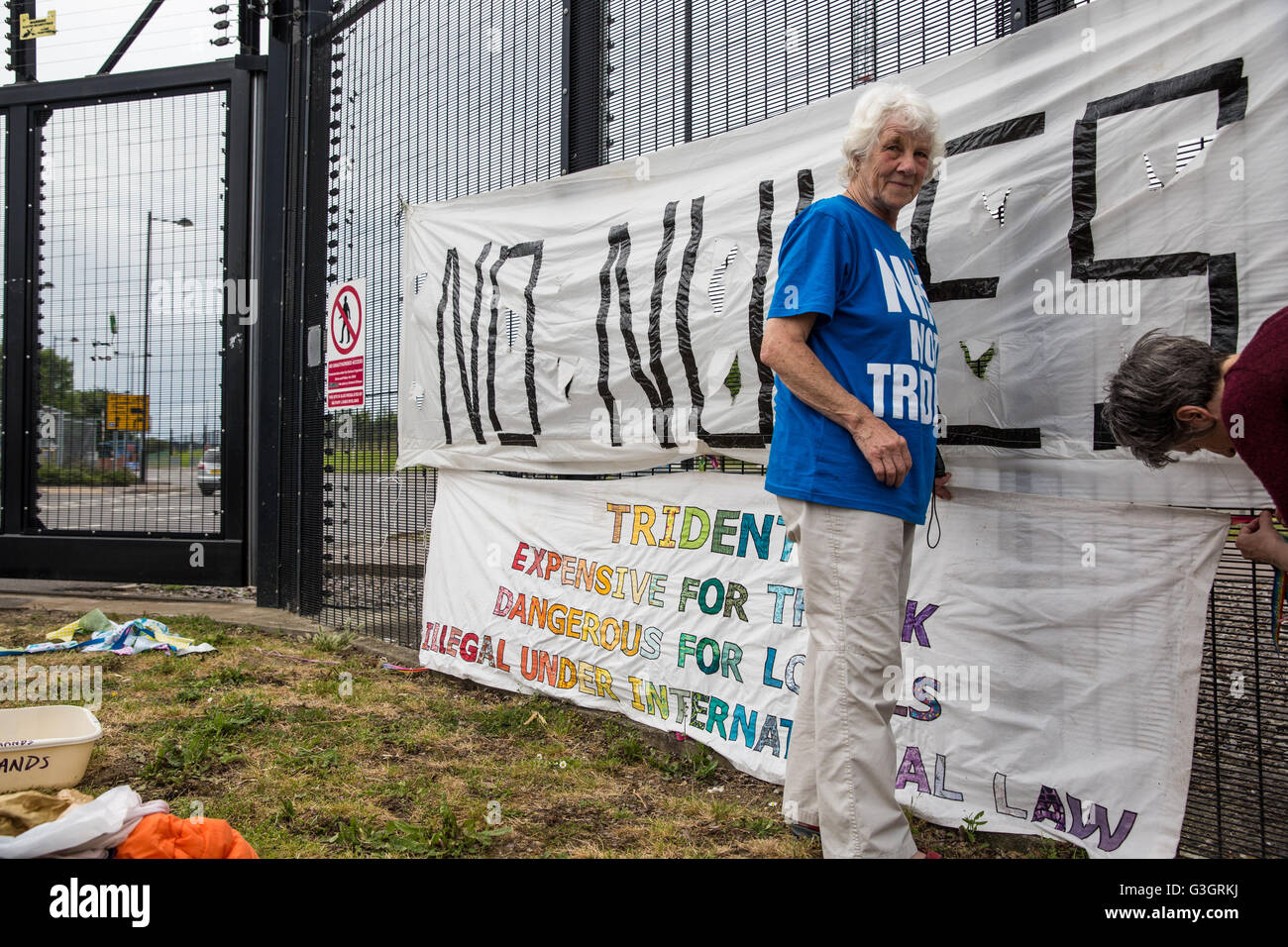Burghfield, UK. 11 Juin, 2016. Ex-Greenham les militants de la paix commune accrocher des bannières sur la clôture de périmètre à AWE Burghfield sur la cinquième journée consécutive d'un blocus de l'entrée des livraisons dans le cadre d'un mois d'action contre le renouvellement du Trident destiné "aux blocus, à occuper et à perturber l'usine" responsable de l'assemblage final de Trident monté des têtes nucléaires. Credit : Mark Kerrison/Alamy Live News Banque D'Images