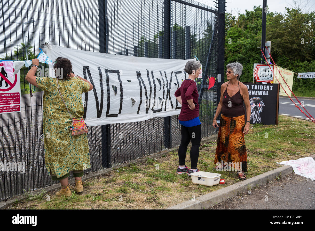 Burghfield, UK. 11 Juin, 2016. Les militants de la paix réorganiser une banderole et des drapeaux suspendus à la clôture périphérique de l'AWE Burghfield sur la cinquième journée consécutive d'un blocus de l'entrée des livraisons dans le cadre d'un mois d'action contre le renouvellement du Trident destiné "aux blocus, à occuper et à perturber l'usine" responsable de l'assemblage final de Trident monté des têtes nucléaires. Credit : Mark Kerrison/Alamy Live News Banque D'Images