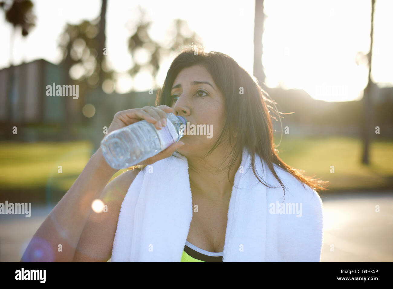 Femme avec une serviette sur les épaules l'eau potable de la bouteille en plastique Banque D'Images