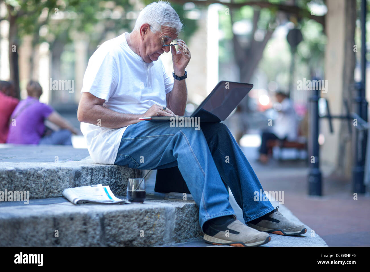 Homme portant des lunettes pour lire sur ordinateur portable city Banque D'Images