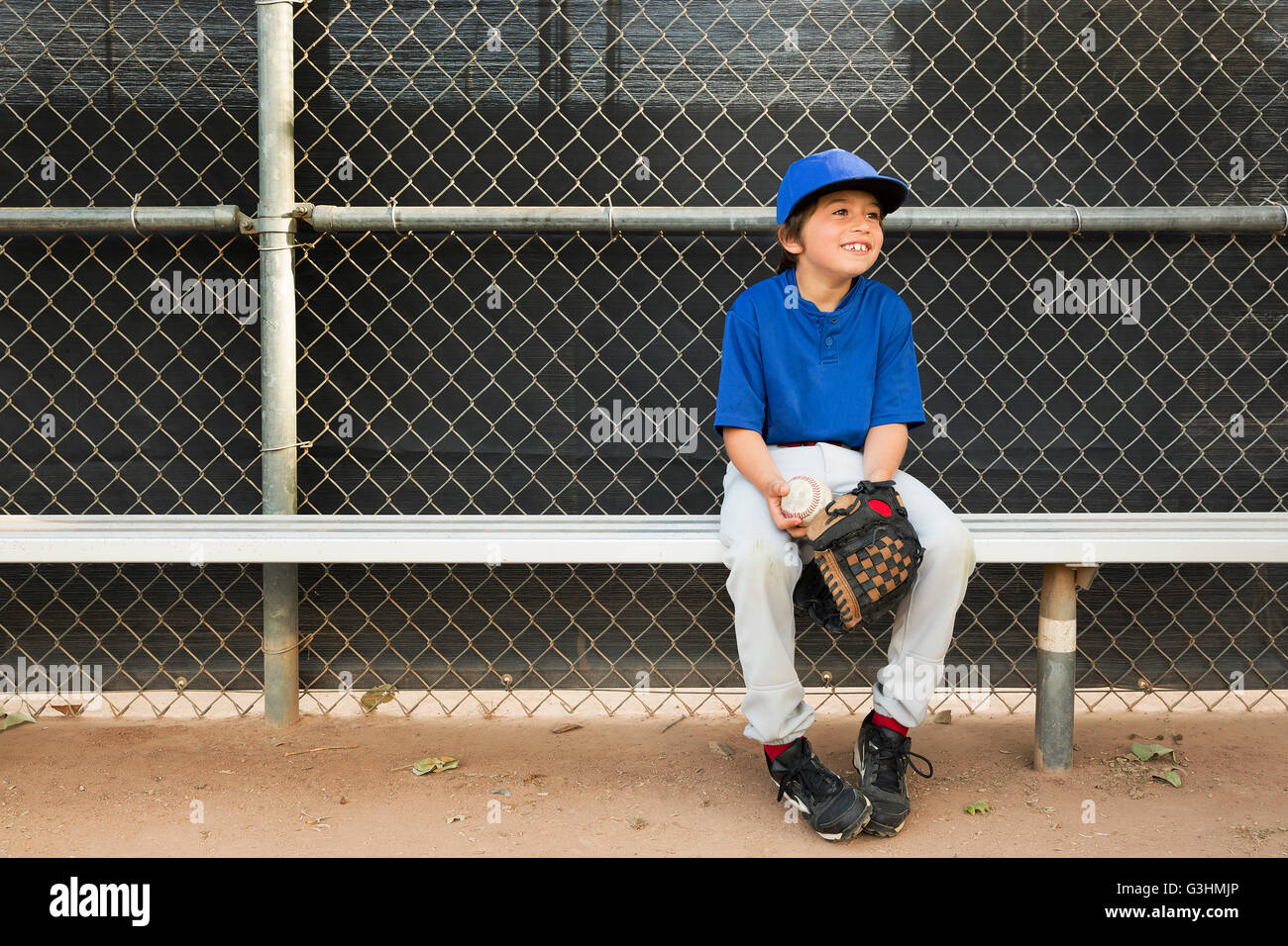 Garçon assis sur un banc à l'entraînement de base-ball Banque D'Images