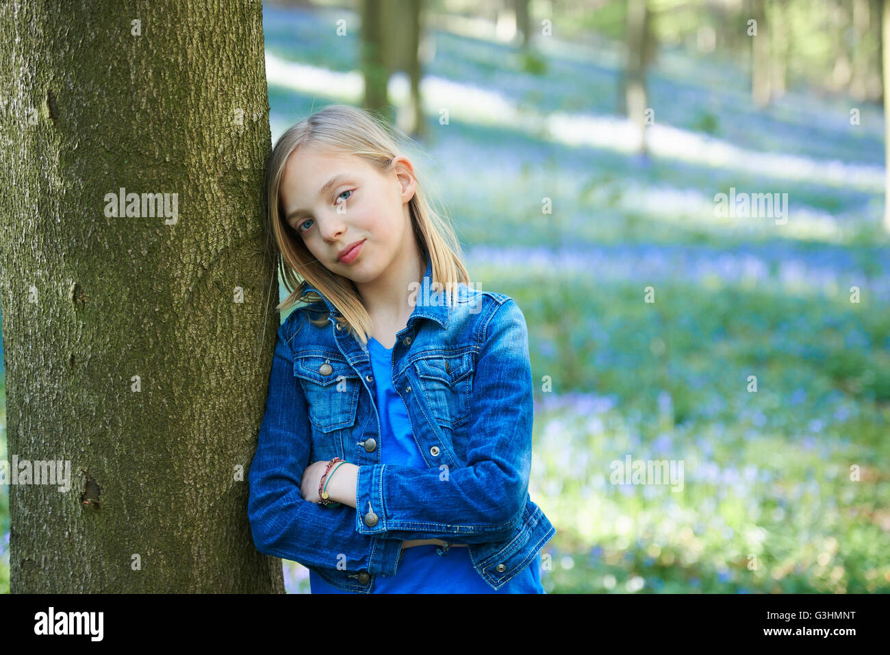 Portrait of Girl leaning against tree in forest, bluebell Hallerbos, Bruxelles, Belgique Banque D'Images