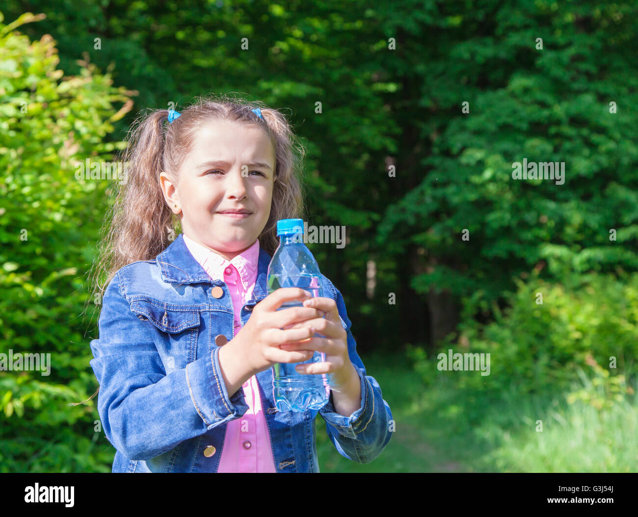 Veste en jean fille en tenant une bouteille d'eau libre en plein air Banque D'Images