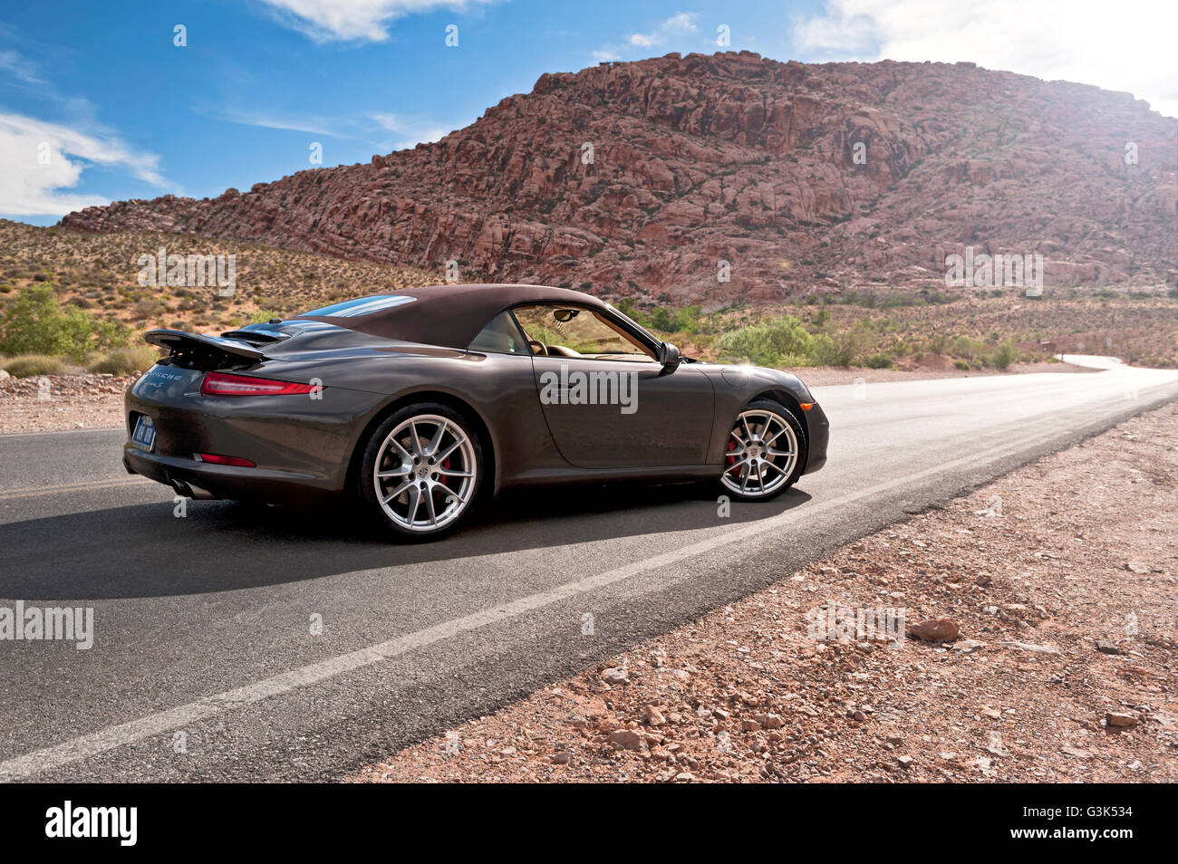 Vue latérale d'une Porsche 911 Carrera S sur une route de montagne du désert Banque D'Images