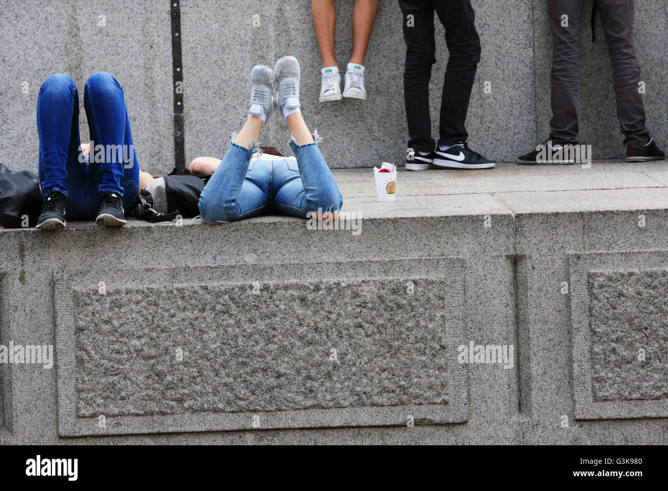 Plusieurs personnes se trouvant / Debout / Assis sur la base de la Colonne Nelson à Trafalgar Square à Londres, Angleterre Banque D'Images