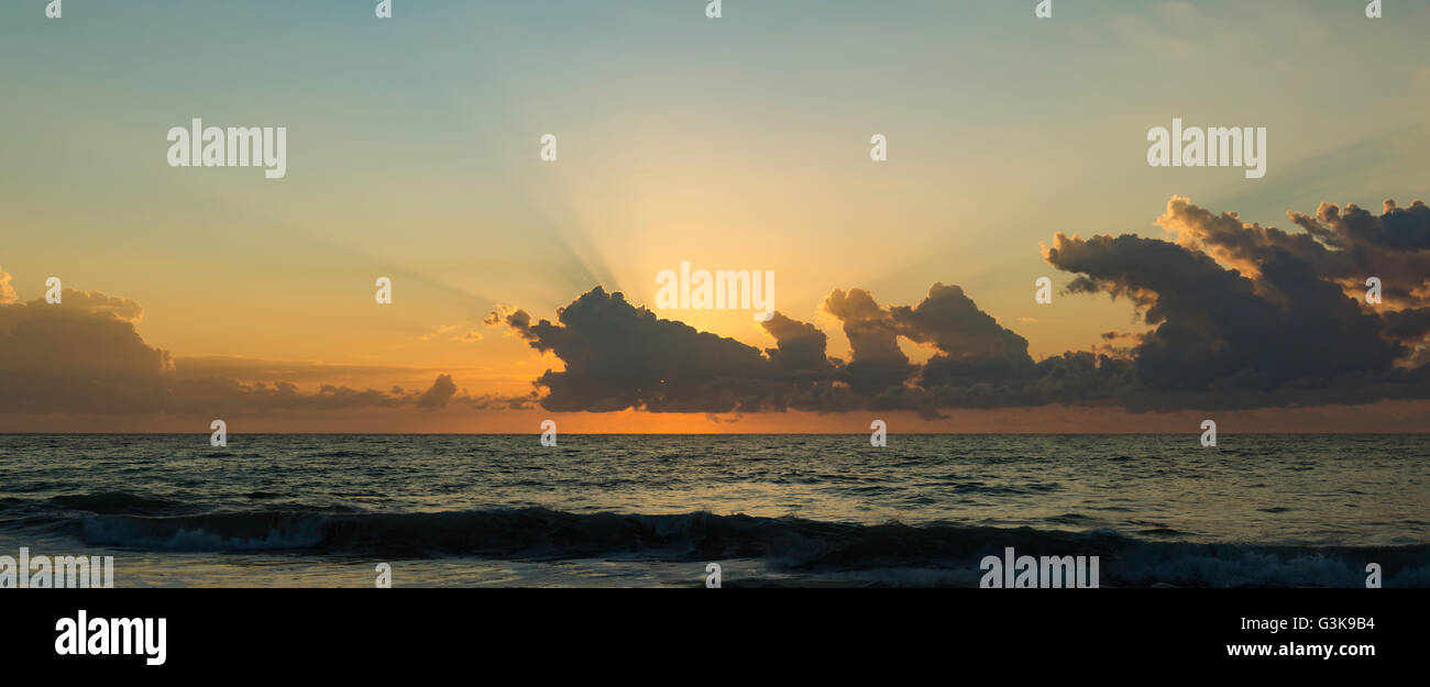 Le soleil se lève derrière les nuages du matin sur une plage sur la côte orientale de l'Australie Banque D'Images