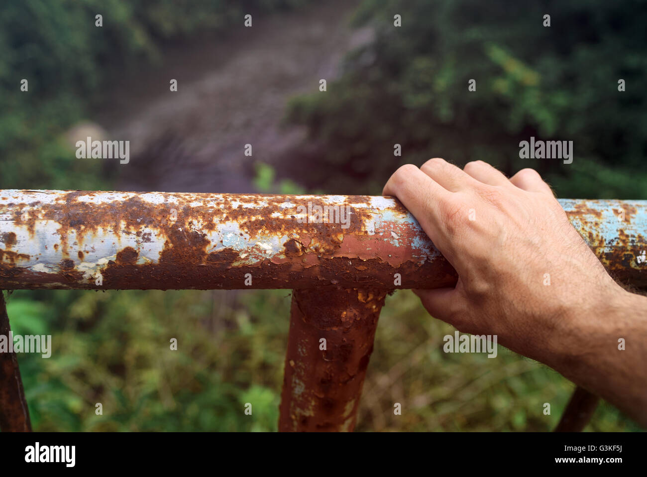 La main de préhension mâle une clôture rouillée river bridge, concept de tendances suicidaires, sautant par dessus le bord. Banque D'Images