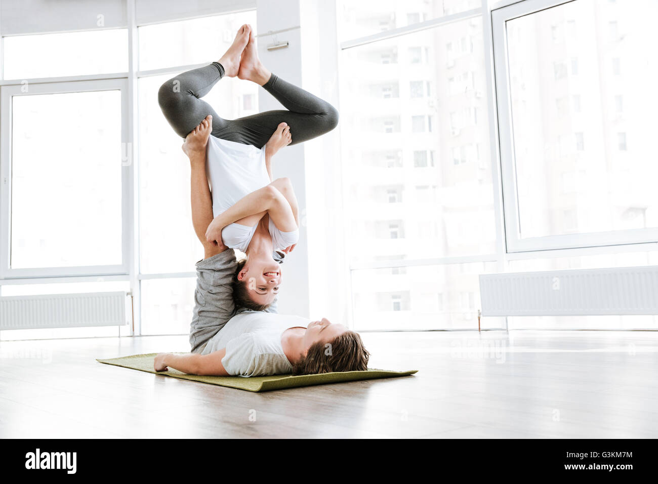 Cheerful young man et woman doing yoga acro au pair in studio Banque D'Images