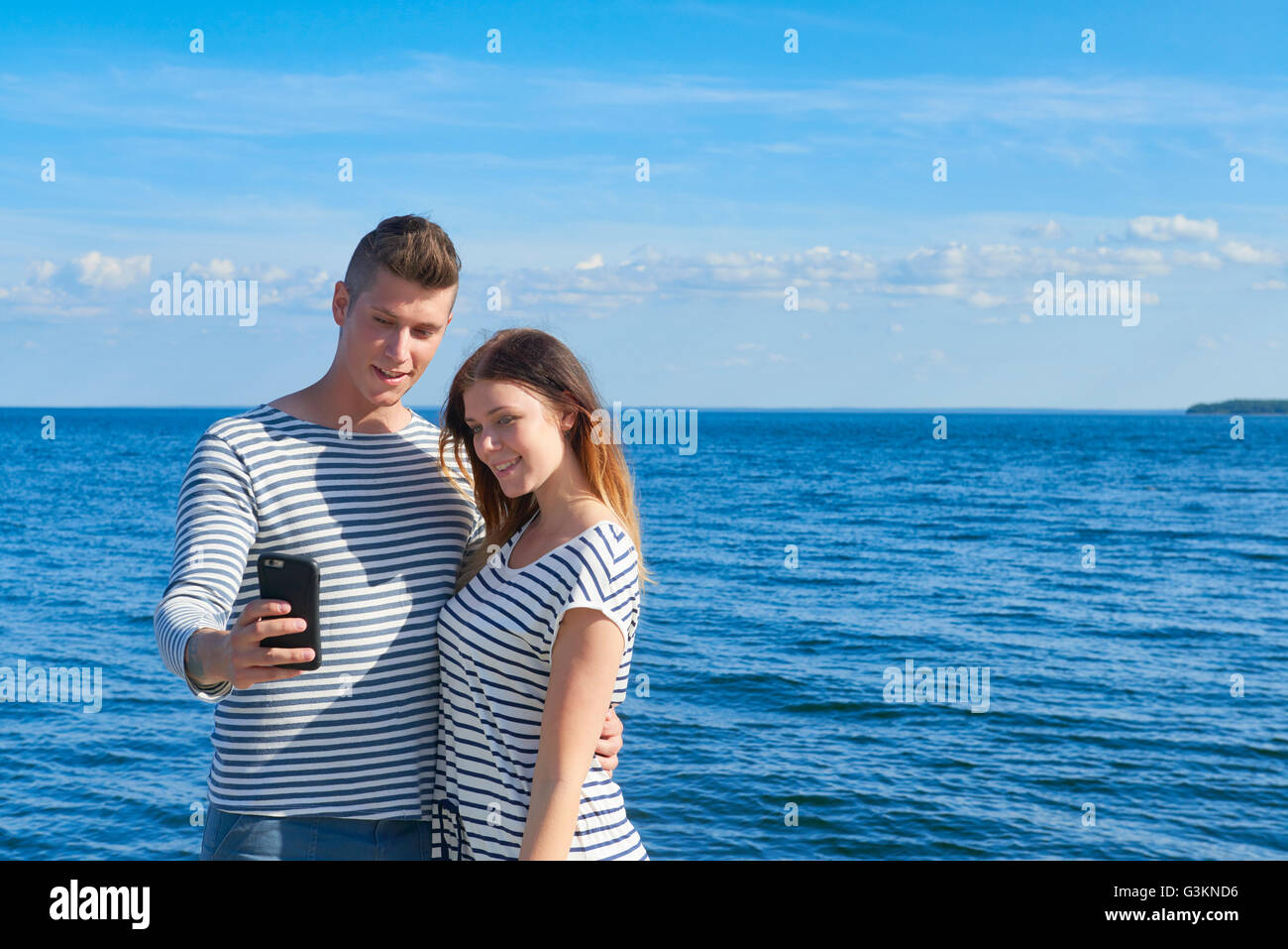 Jeune couple standing par mer, taking self portrait using smartphone Banque D'Images