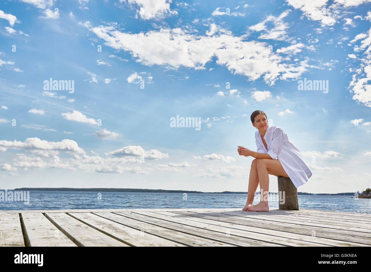 Jeune femme assise sur le post sur l'embarcadère en bois, à l'écart Banque D'Images