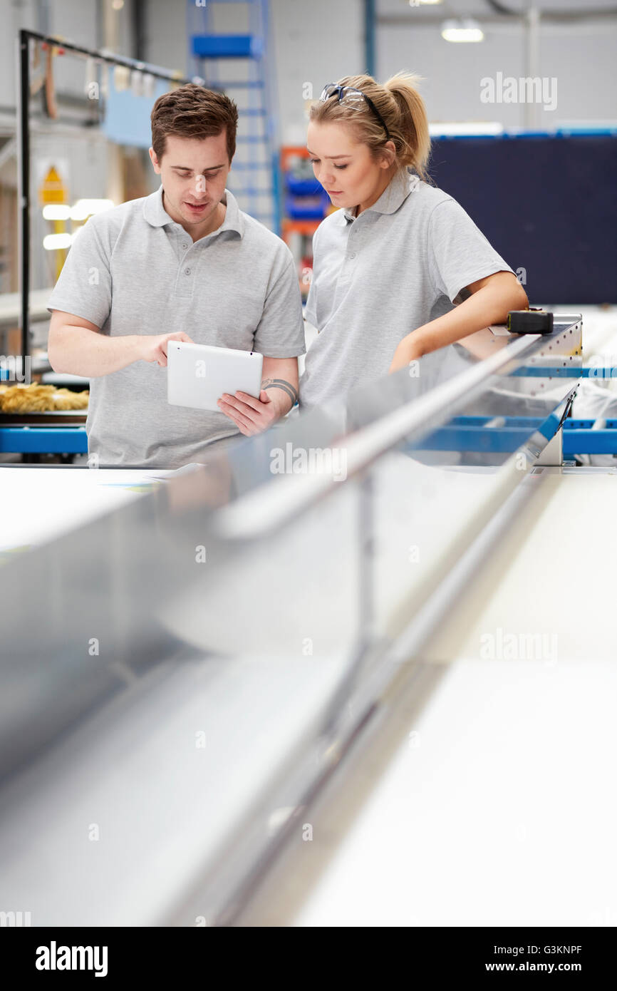 Manager et travailleur féminin looking at digital tablet sur la ligne de production en usine Banque D'Images