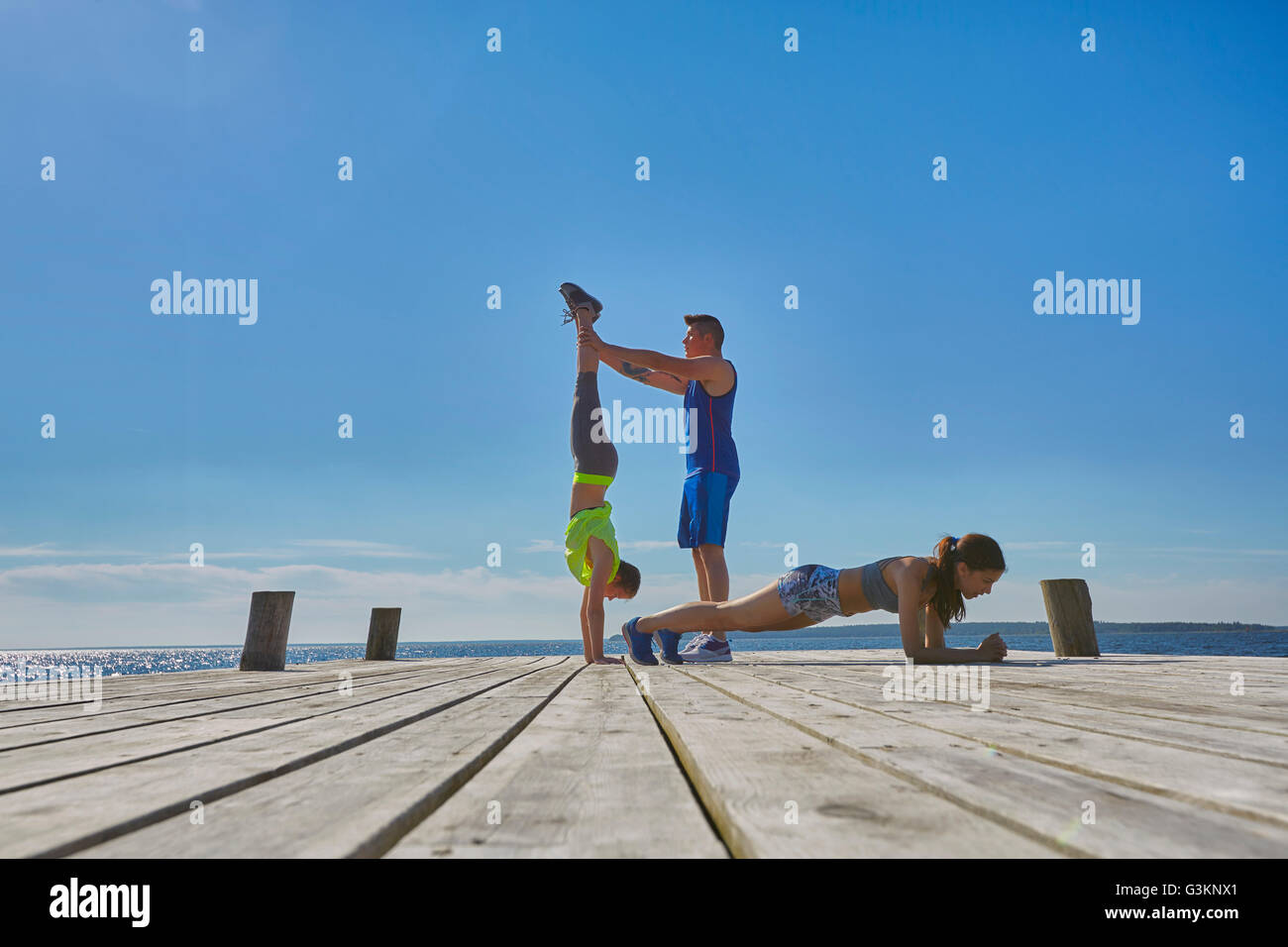 Amis de pier faisant handstands et poussez se lève Banque D'Images