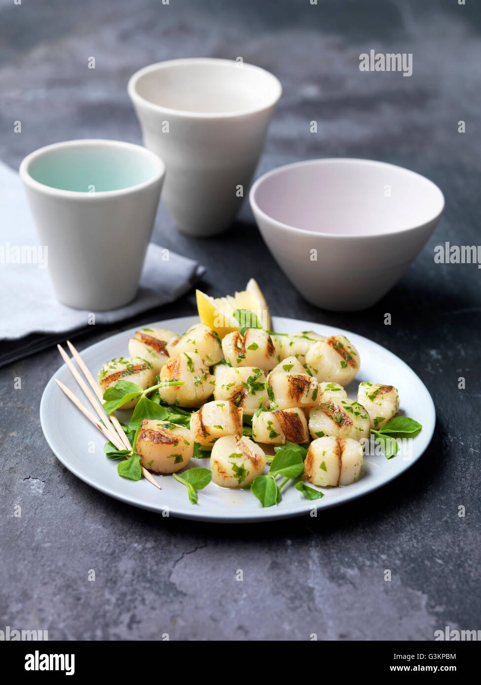 Pétoncles cuits au feu sur la plaque avec des herbes et tranche de citron Banque D'Images