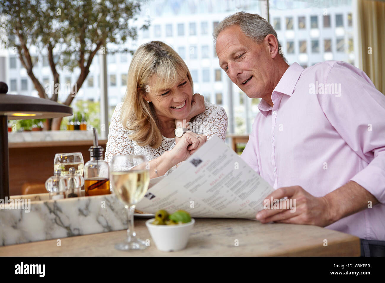 Mature dating couple reading menu au restaurant table Banque D'Images