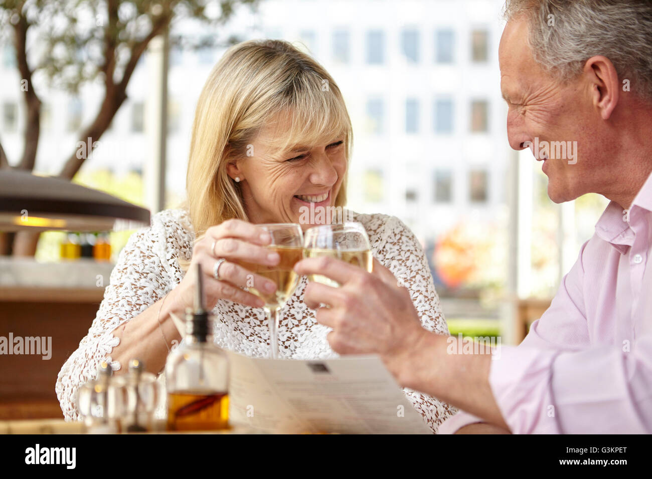 Couple mature dating soulever un verre de vin blanc au restaurant table Banque D'Images