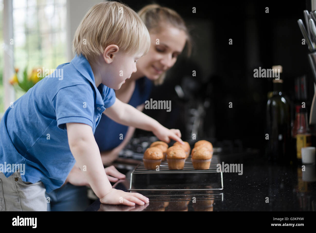 Mère et fils attendent des petits muffins refroidir Banque D'Images