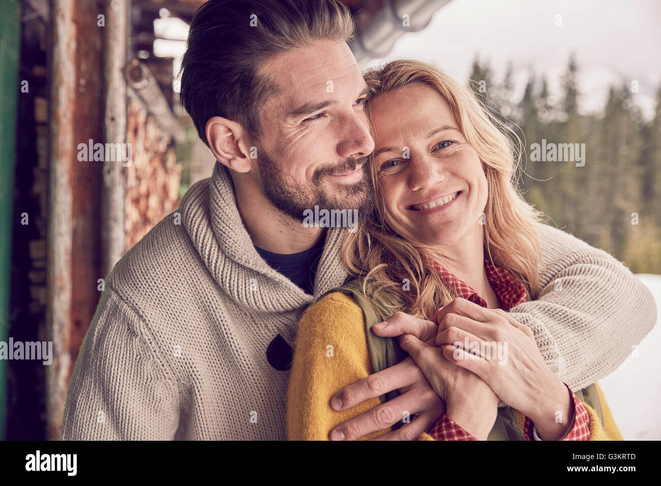 Portrait of romantic couple standing outside log cabin en hiver, Elmau, Bavière, Allemagne Banque D'Images