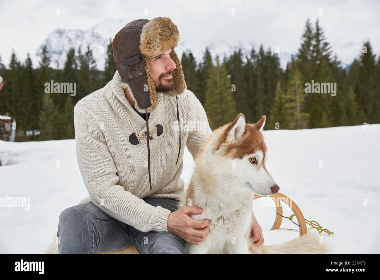 Jeune homme portant un chapeau de trappeur dans la neige, Husky Elmau, Bavière, Allemagne Banque D'Images