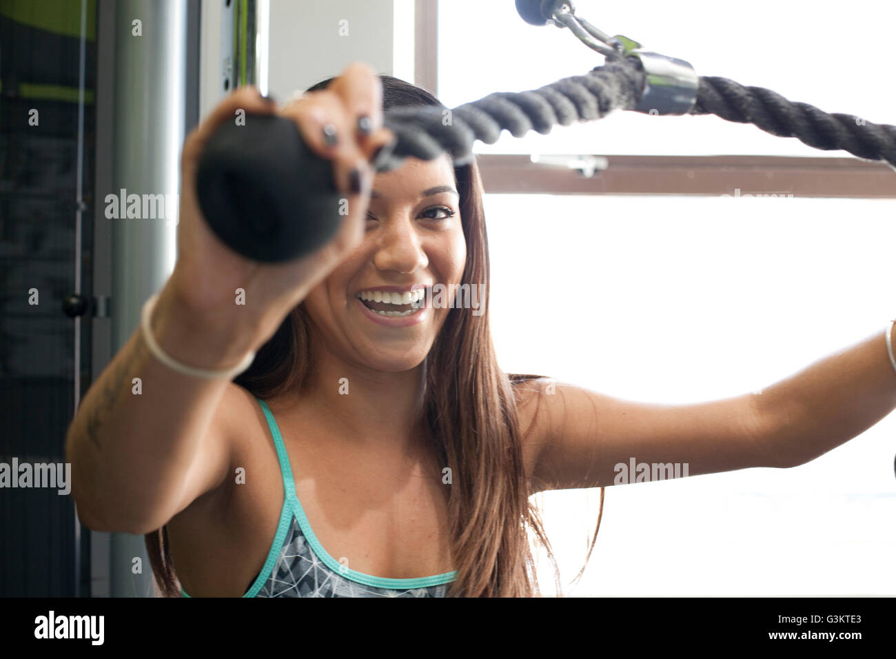 Femme dans une salle de sport à l'aide de machine d'exercice à la caméra en souriant Banque D'Images