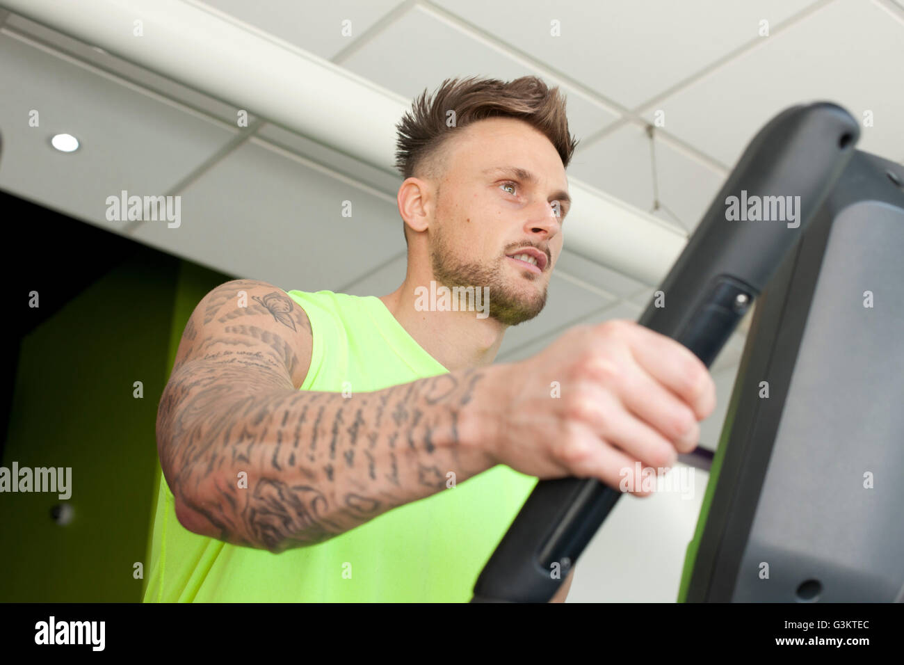 Tattooed man in gym à l'aide de machine d'exercice Banque D'Images