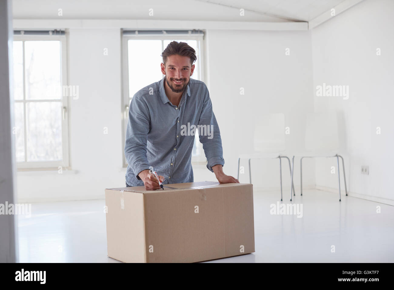 Portrait de jeune homme écrit sur carton fort whilst moving house Banque D'Images