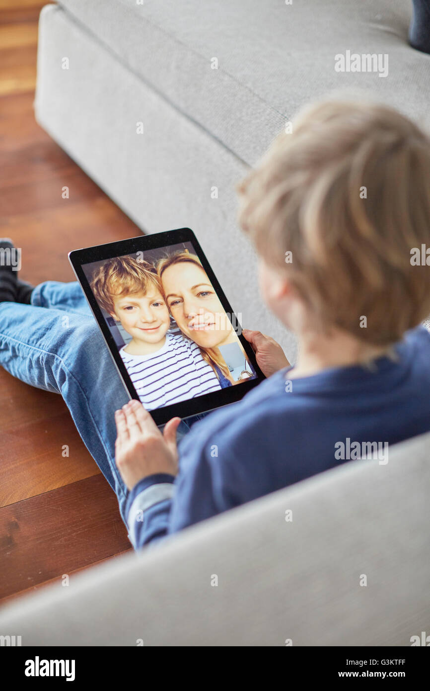 Garçon assis sur le plancher de parler à mère et son frère sur tablette numérique appel vidéo Banque D'Images