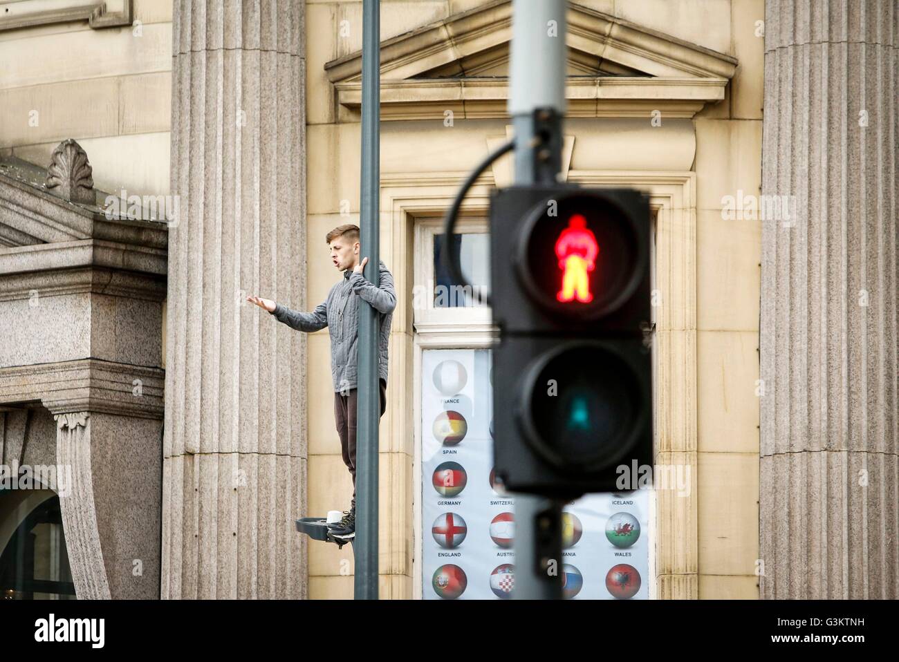 Un homme se tient sur un lampadaire en place de la ville de Leeds, attirer le trafic à l'arrêt après la route au-dessous de lui a été fermé par la police. Banque D'Images