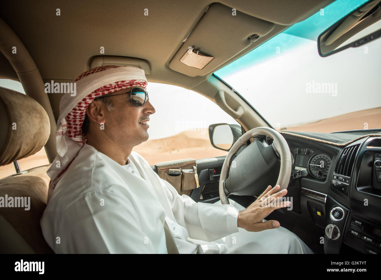 Middle Eastern homme portant des vêtements traditionnels de la conduite hors route véhicule en désert, Dubaï, Émirats Arabes Unis Banque D'Images