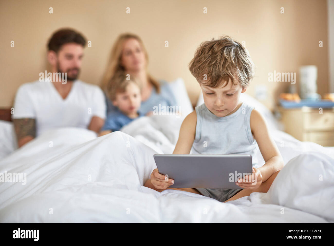 Garçon sur le lit des parents using digital tablet Banque D'Images