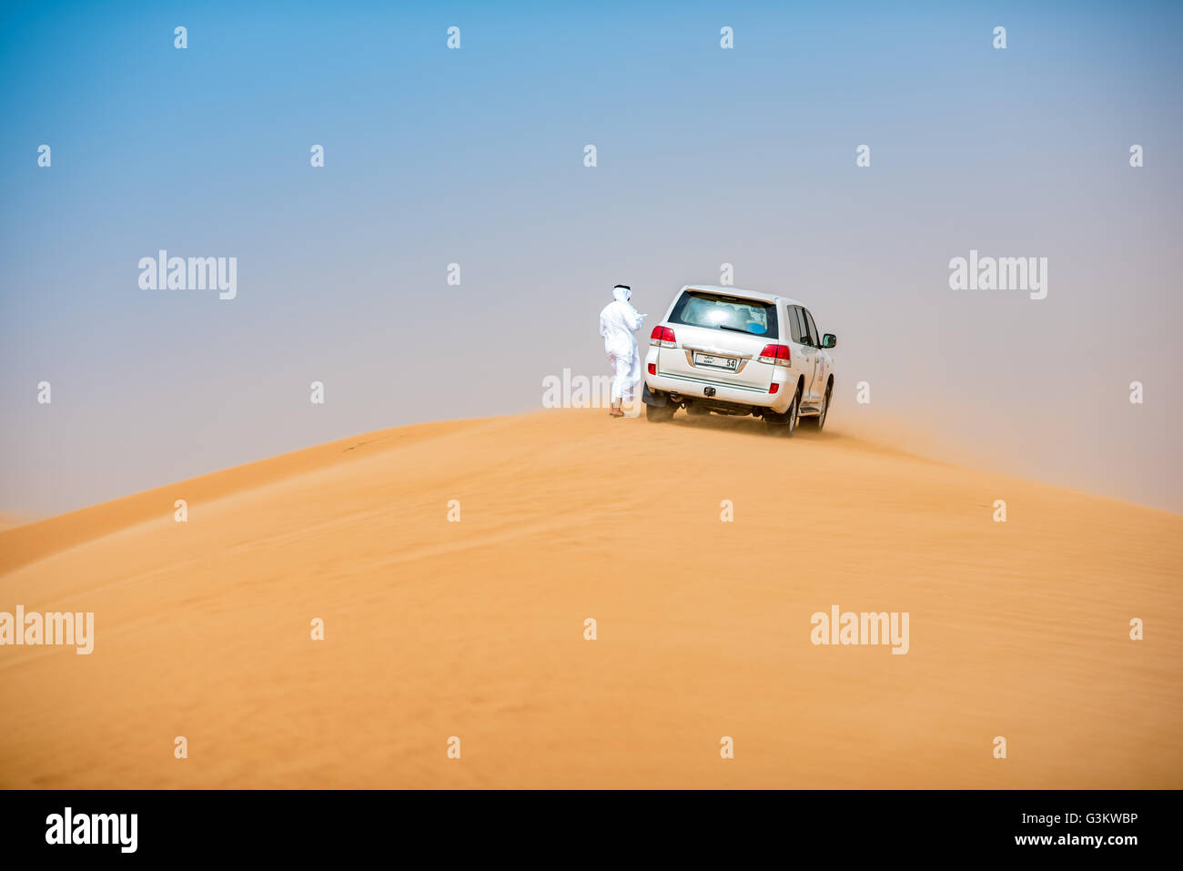 Middle Eastern homme portant des vêtements traditionnels avec off road véhicule stationné sur les dunes du désert, Dubaï, Émirats Arabes Unis Banque D'Images