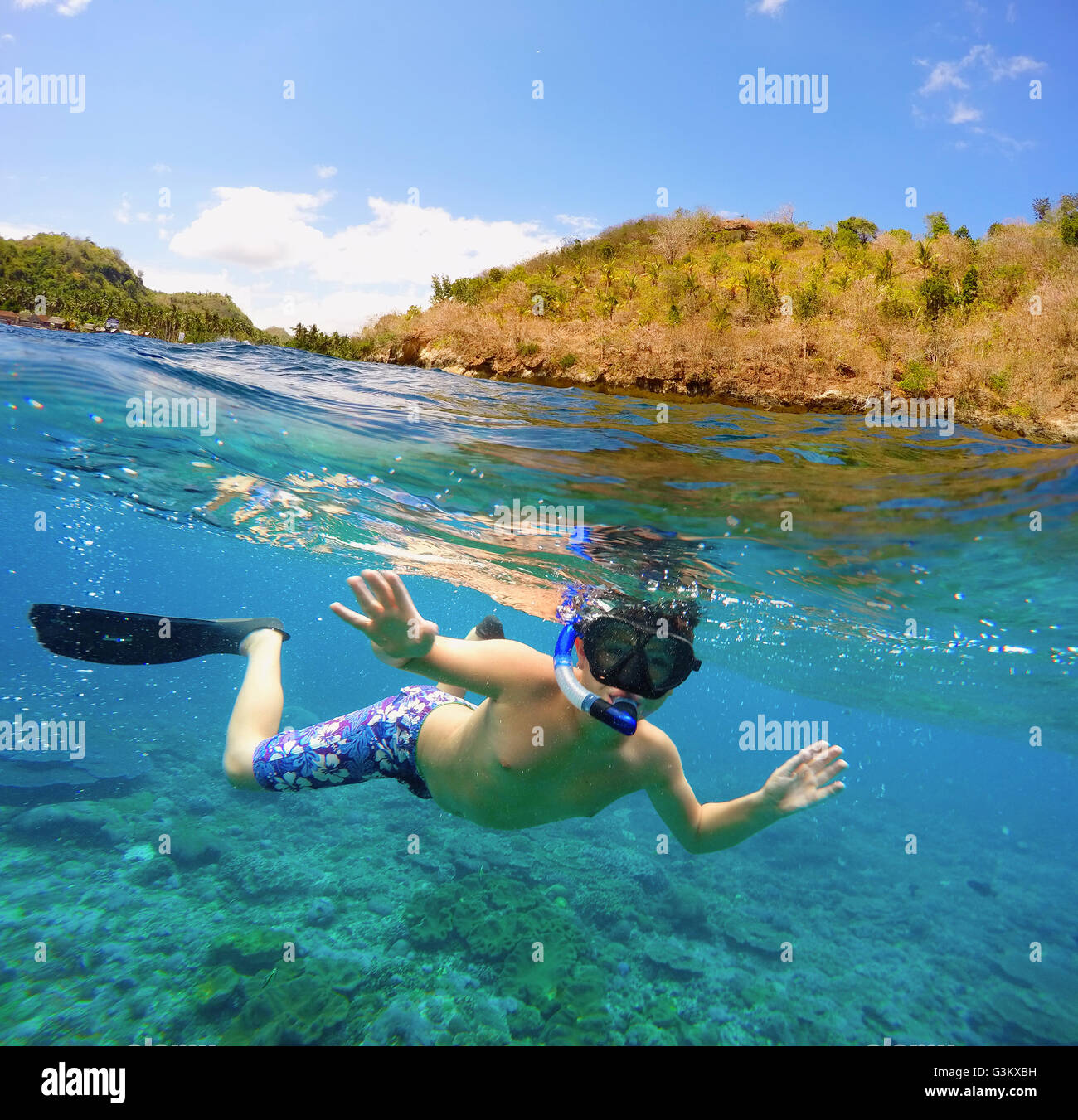 Vue fractionnée sous-marins et de surface dans les tropiques paradis avec masque et tuba des poissons de récifs coralliens et de garçon, au-dessus de la flottaison, belle vi Banque D'Images