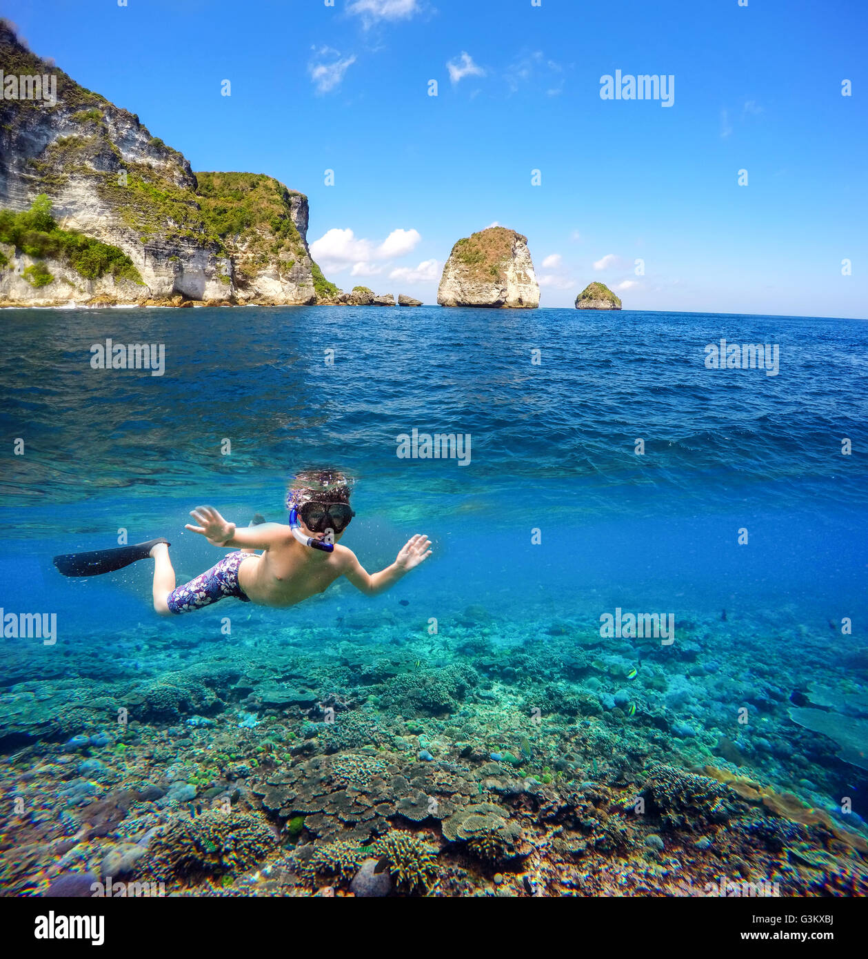 Vue fractionnée sous-marins et de surface dans les tropiques paradis avec masque et tuba des poissons de récifs coralliens et de garçon, au-dessus de la flottaison, belle vi Banque D'Images