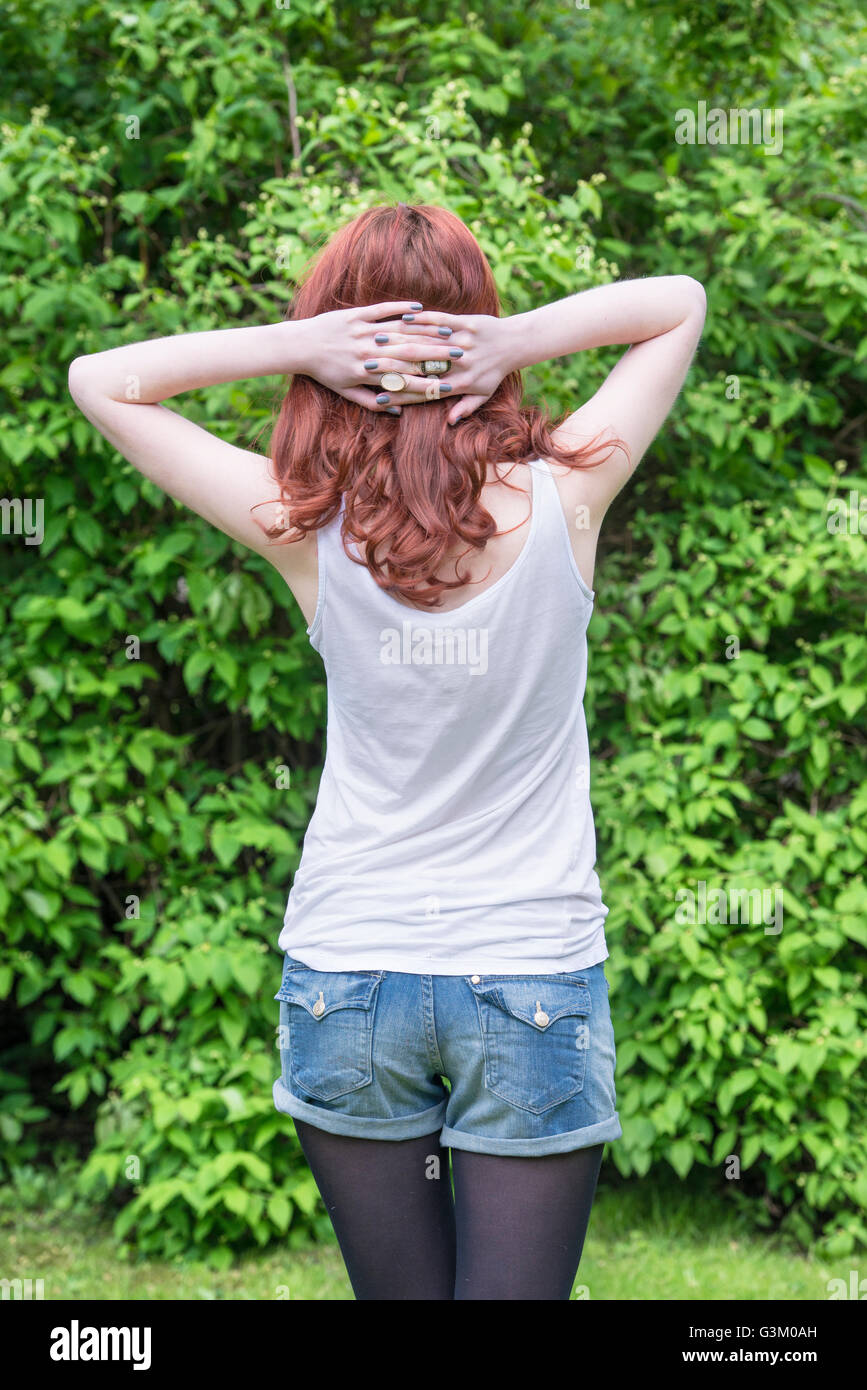 Vue arrière de jeune femme traversant ses mains derrière sa tête Banque D'Images