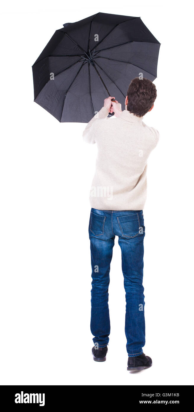 Vue arrière de l'homme en jeans sous un parapluie. Jeune homme debout. Vue arrière Vue arrière. collection les gens de personne. Plus isolé sur fond blanc. Le mec est en essayant de garder le vent petits parapluie. Banque D'Images