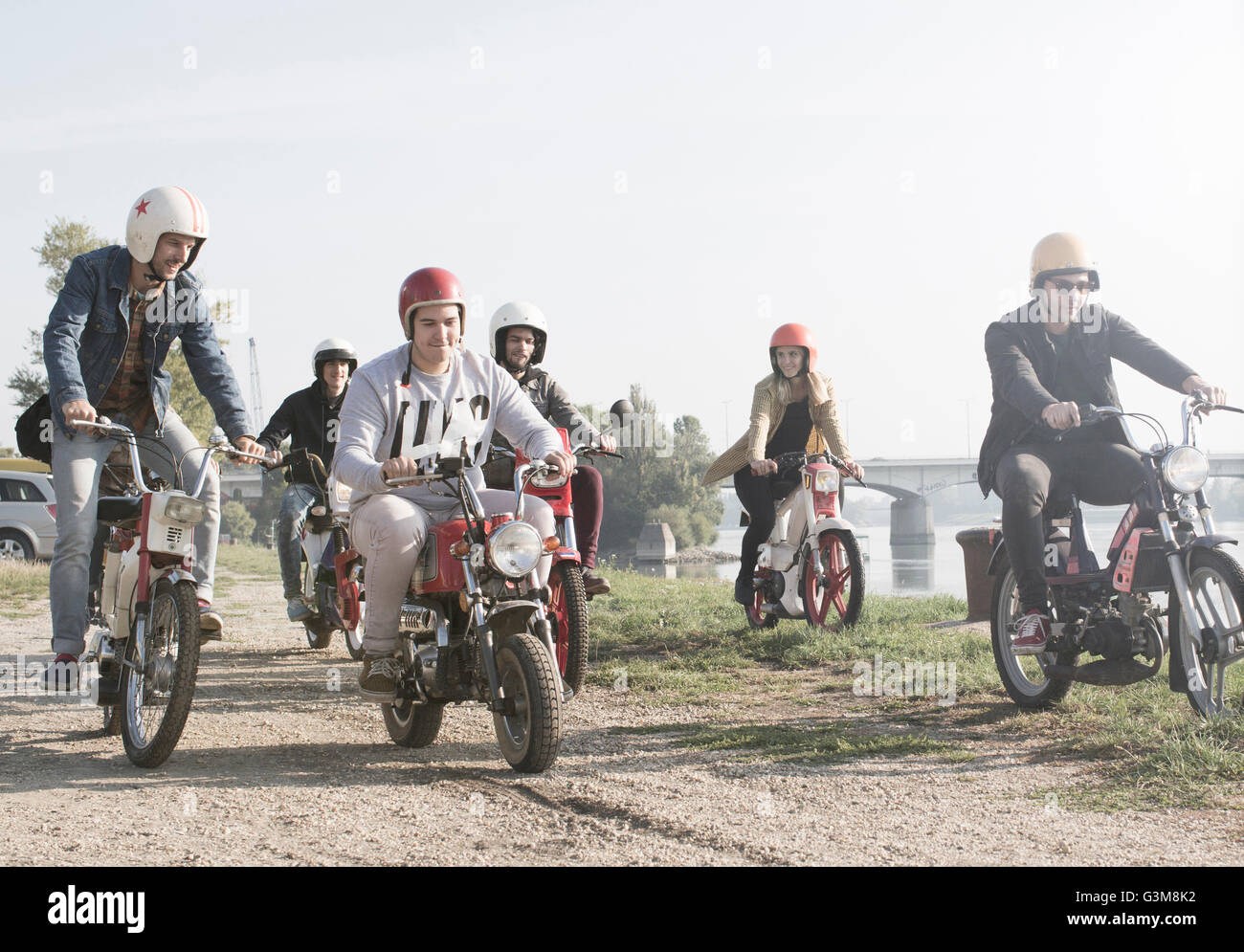 Groupe d'amis au bord du lac de cyclomoteurs équitation Banque D'Images