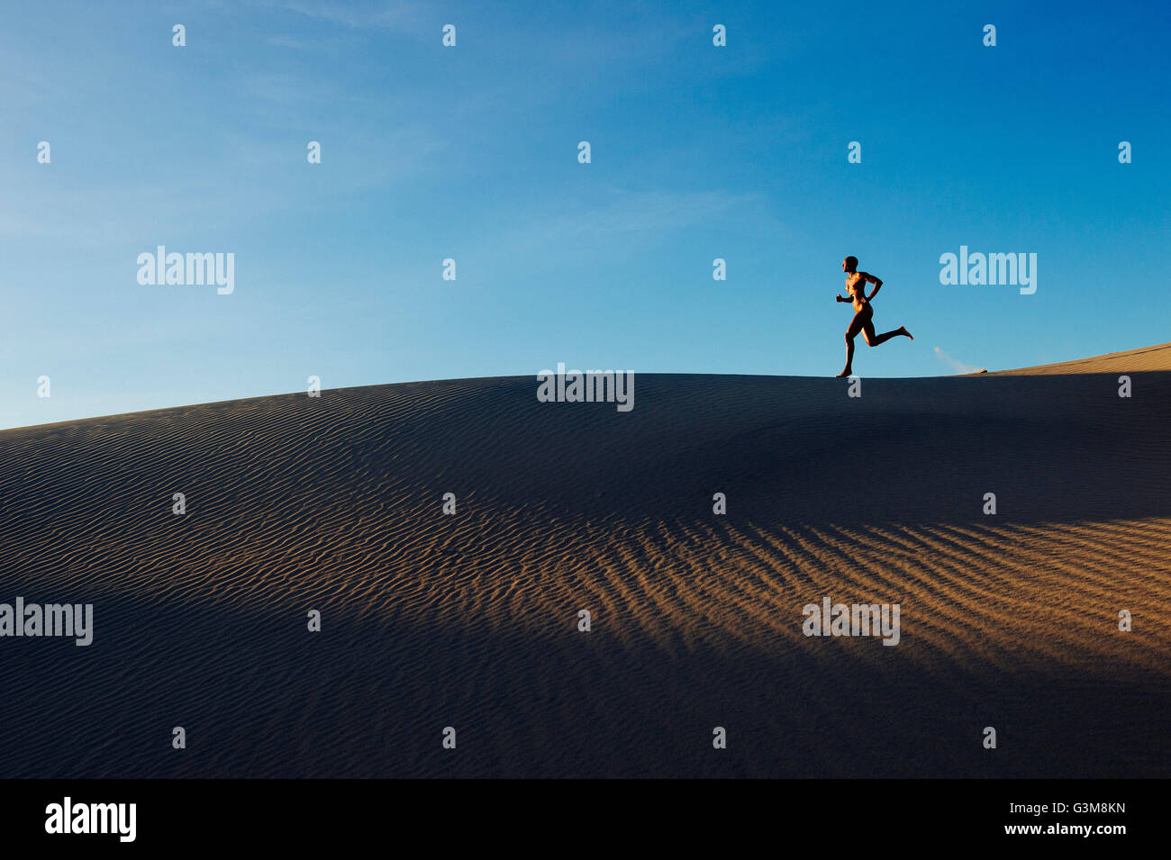 Femme nue dans le désert en marche sur dune Banque D'Images