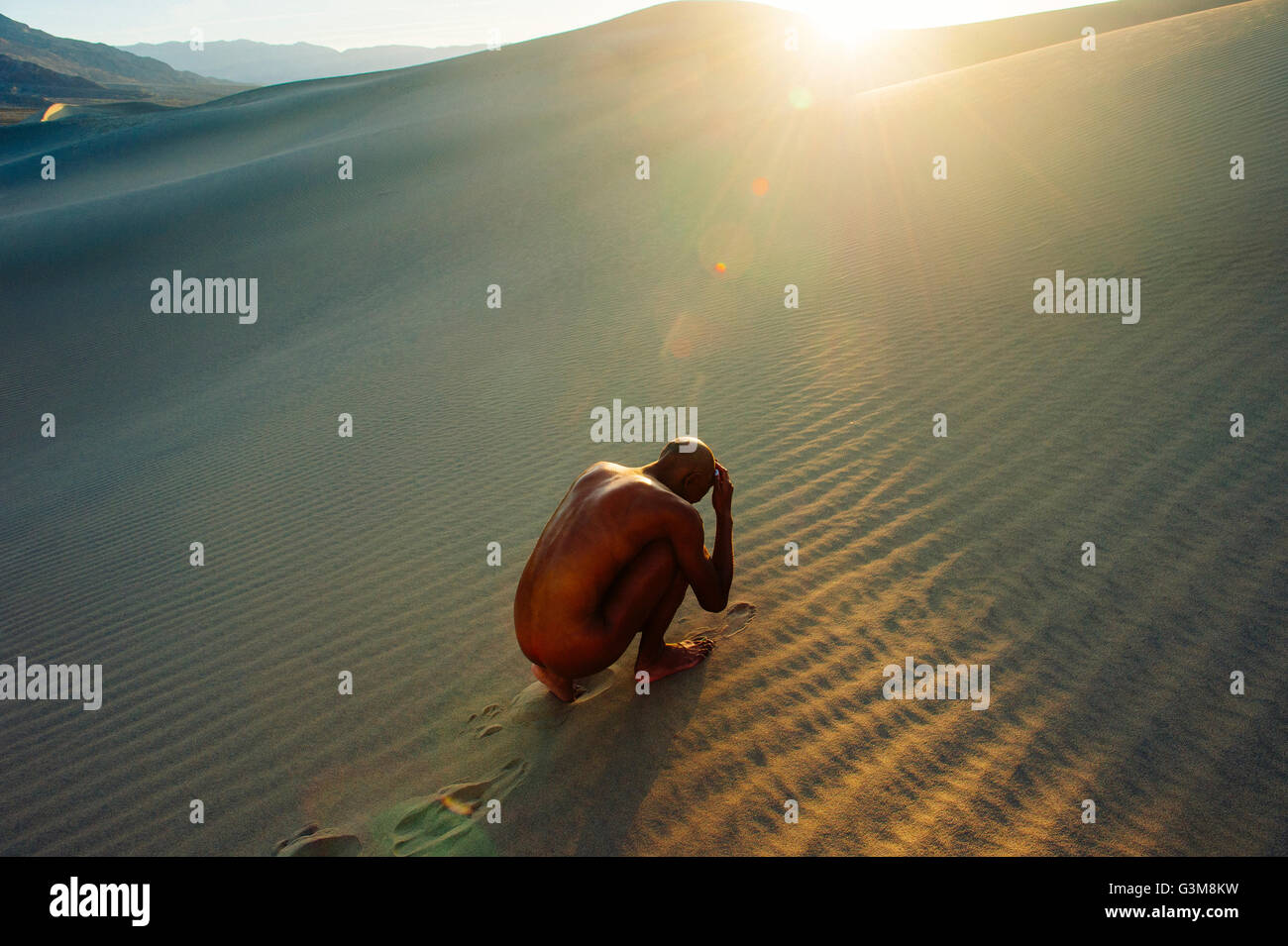 Femme nue se recroquevillant dans desert Banque D'Images