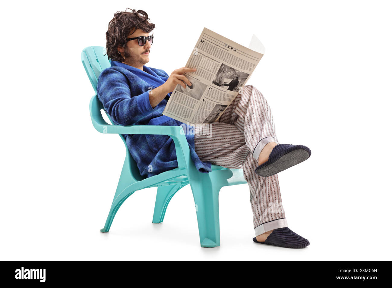 Jeune homme lisant un journal, assis sur une chaise en plastique bleu isolé sur fond blanc Banque D'Images