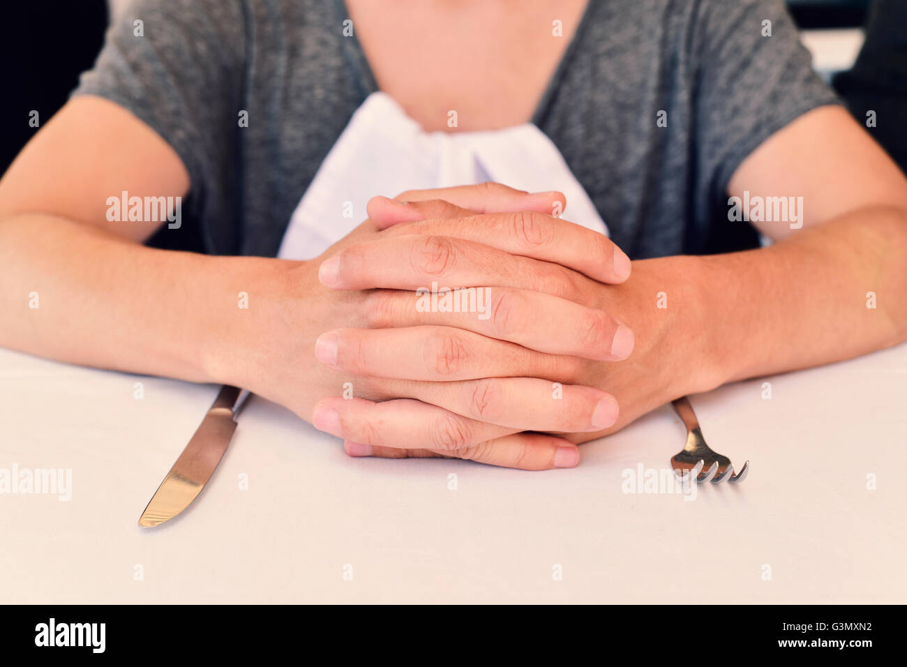 Libre d'un jeune couple assis à une table en attente de l'alimentation, avec ses mains d'un et d'un couteau et une fourchette en fro Banque D'Images