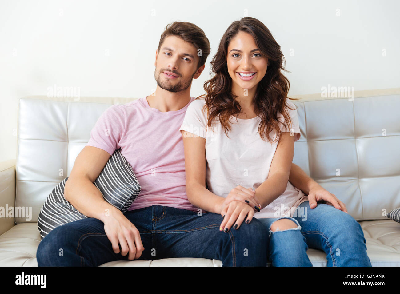 Jeune couple assis sur un canapé isolé sur fond blanc Banque D'Images