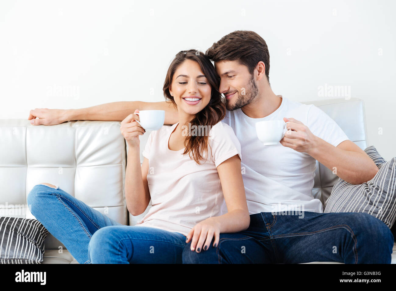 Portrait of a happy couple souriant sur le canapé à boire du café Banque D'Images