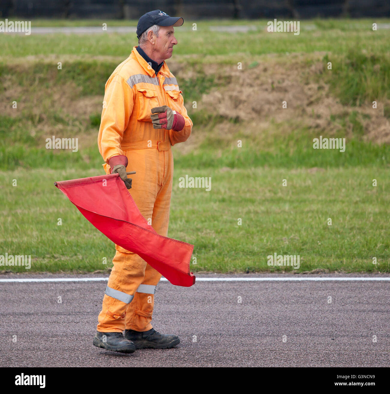 Commissaire de pistes avec drapeau rouge lors d'un événement de sport motorisé. Banque D'Images