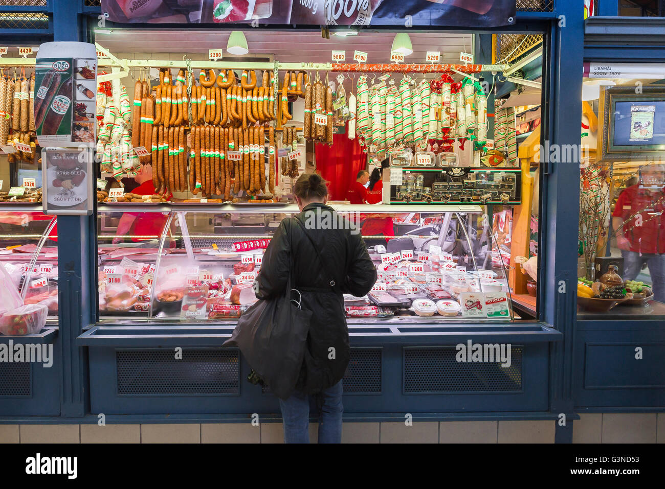 Grand marché de Budapest, une femme achète la viande à l'étal d'un boucher dans le Grand Hall du marché dans le domaine de Jozsefvaros Budapest, Hongrie. Banque D'Images