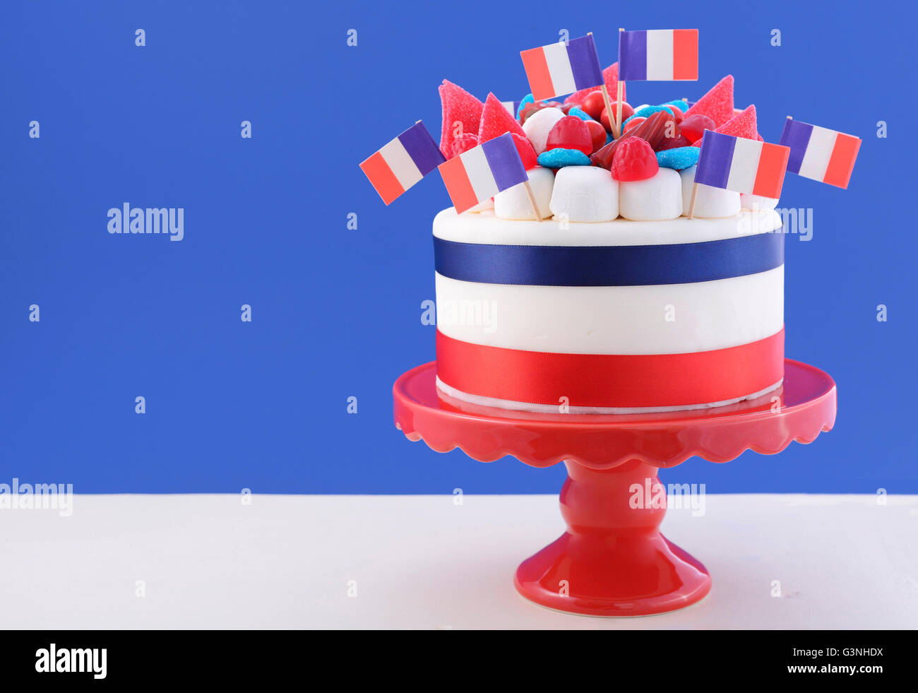 Happy Bastille Day celebration cake avec des drapeaux, guimauve, bonbons, décorations sur un gâteau rouge debout sur un tableau blanc contre un Banque D'Images