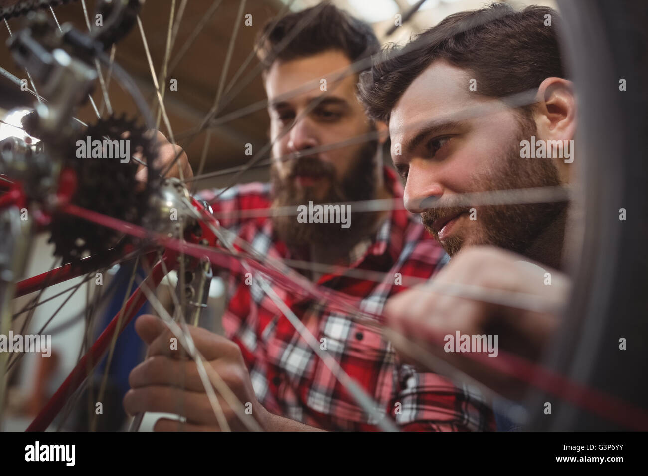 Close up de deux mécaniciens de la réparation d'une roue de bicyclette Banque D'Images